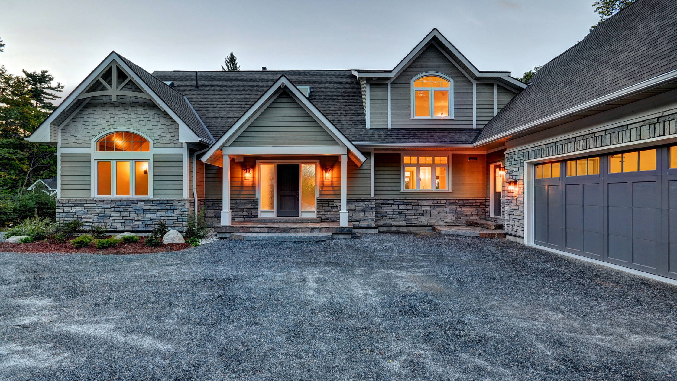 Traditional Muskoka custom cottage with craftsman-style architecture, natural stone accents, and attached garage, representing mid-range finishes typical when considering the cost to build a custom cottage in MuskokaRetryClaude can make mistakes. Please double-check responses.