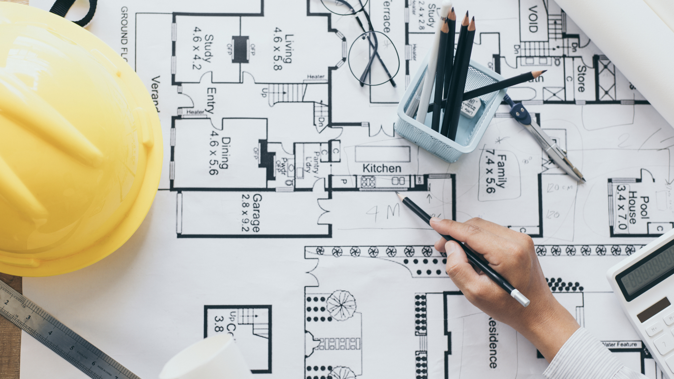 Architectural plans and construction tools laid out on a blueprint—illustrating the early design phase in the timeline to build a custom cottage.

