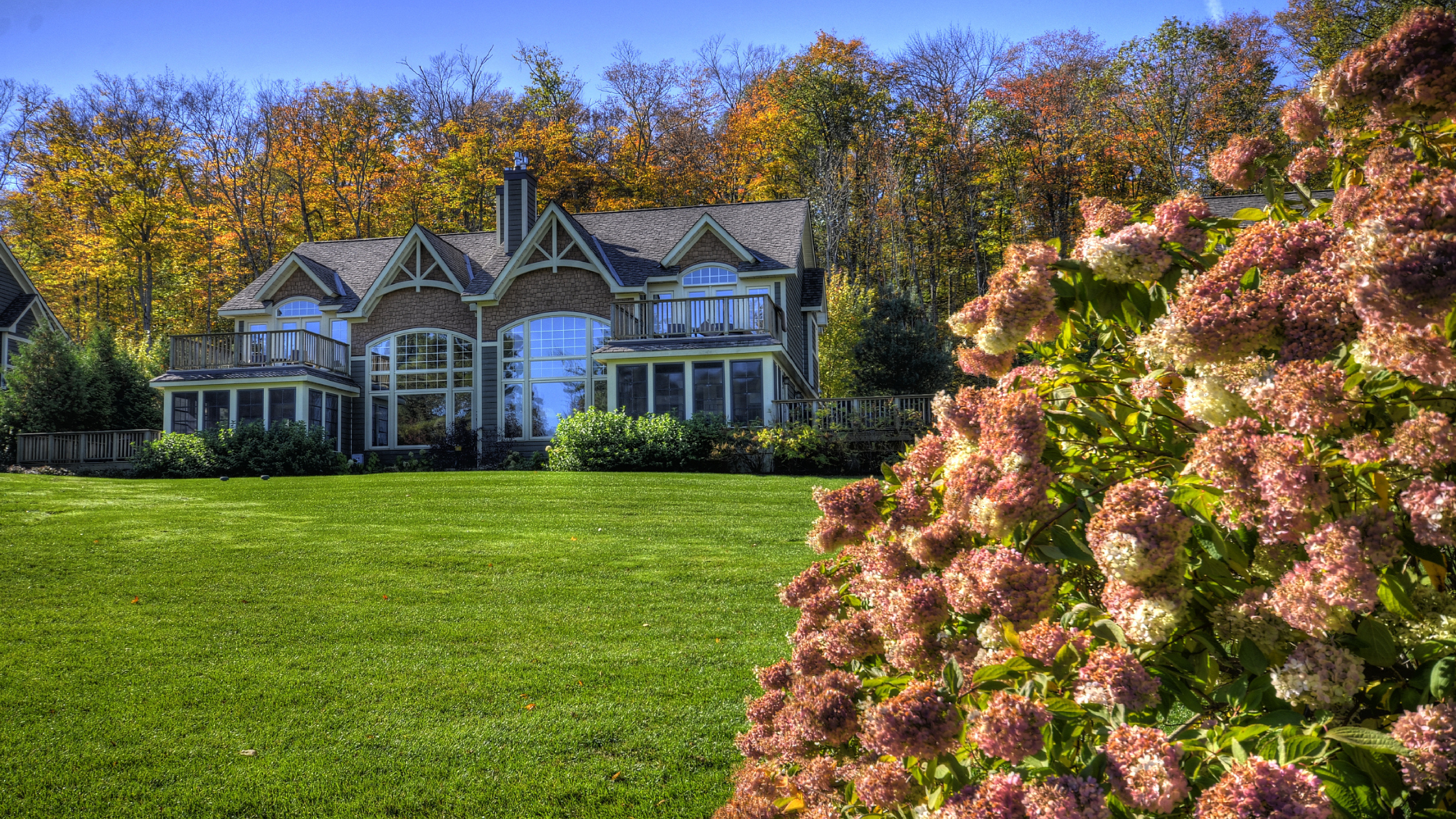 Custom-built Muskoka cottage with landscaped lawn and fall foliage, representing the final stage in the timeline to build a custom cottage.