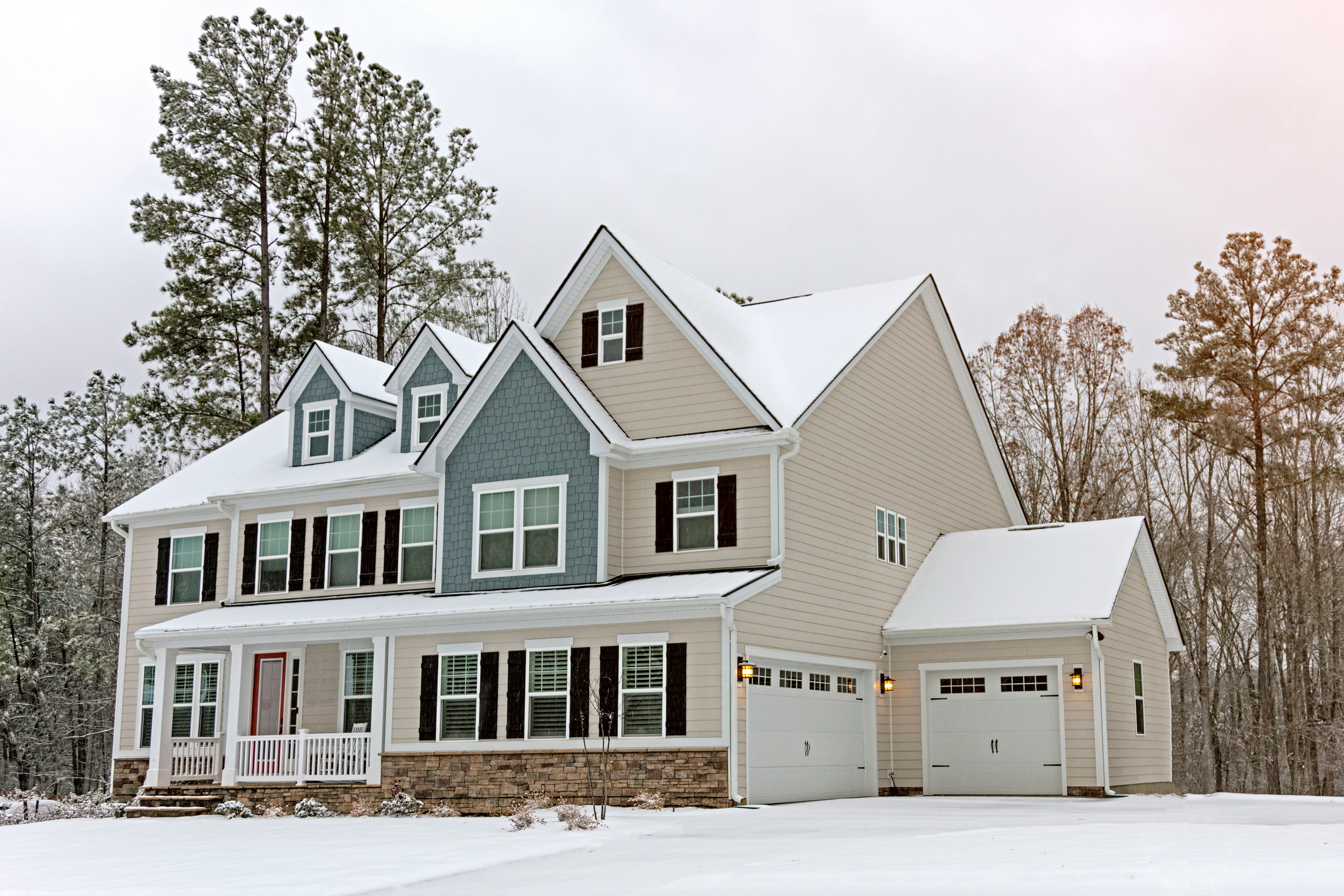 Two-story cottage surrounded by snow, showing the importance of winter cottage maintenance to protect the roof, siding, and foundation.