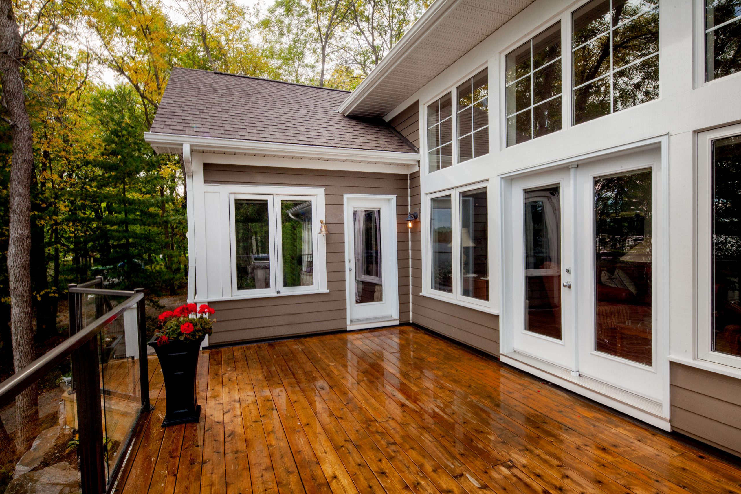 Spacious wooden deck of a custom cottage in Central Ontario’s Cottage Country overlooking the lake and surrounded by trees.