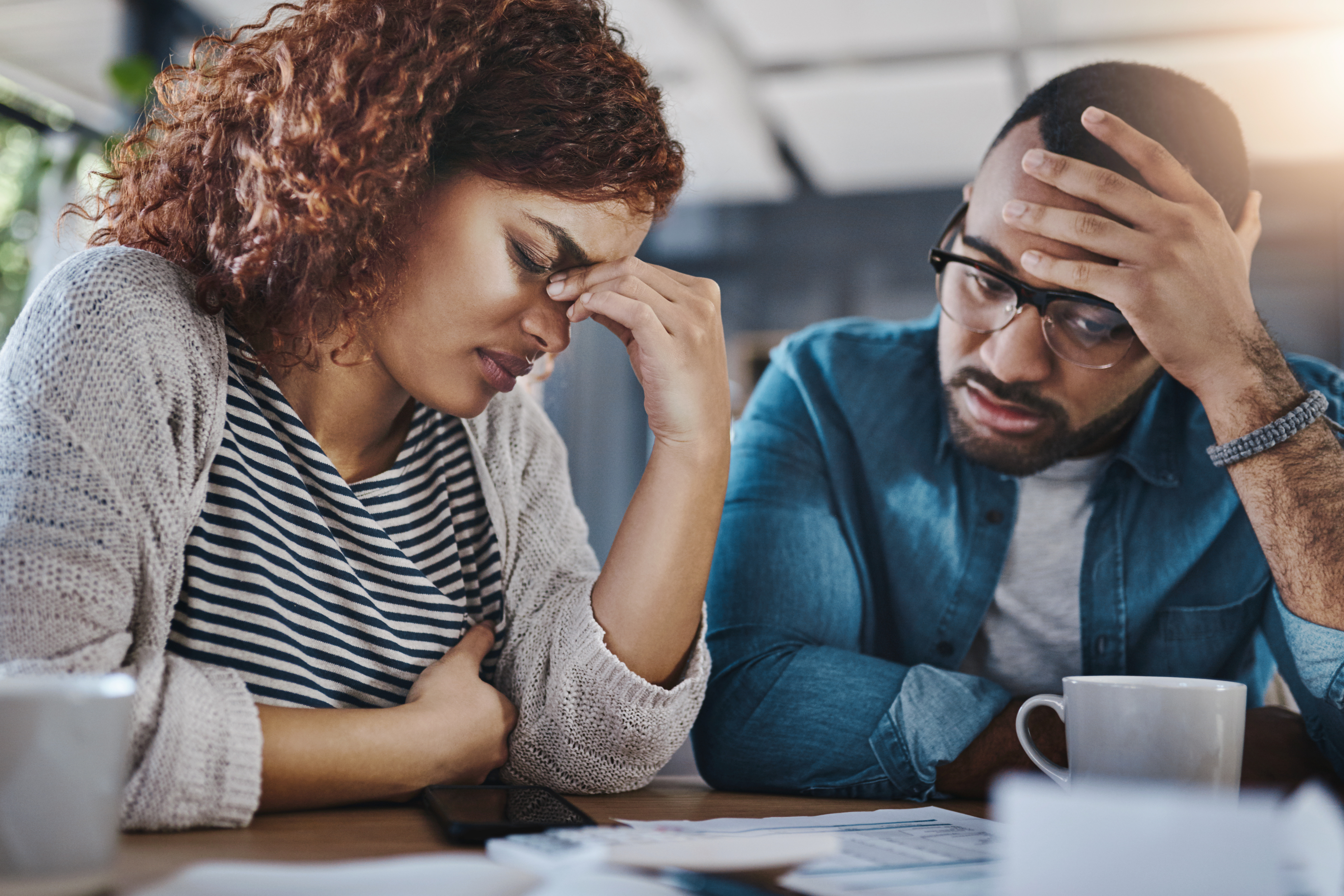 Frustrated couple reviewing unexpected costs — a common red flag you hired the wrong custom home builder due to budget overruns.